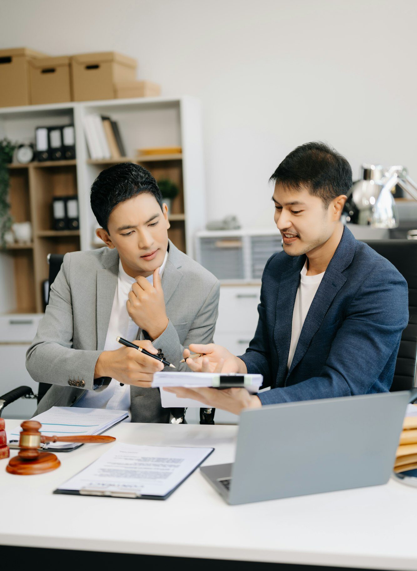 Asian business team and lawyers discussing contract papers sitting at the table.